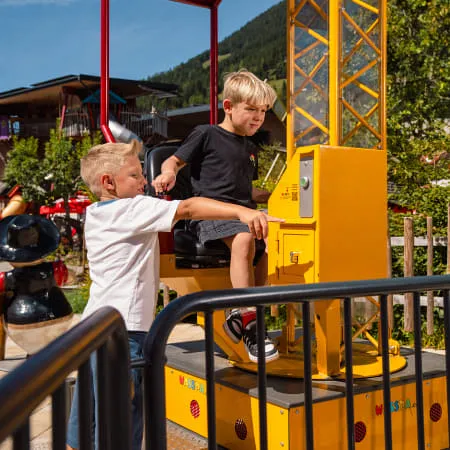 Zwei Kinder an einem gelben Fahrgerät im Erlebnispark