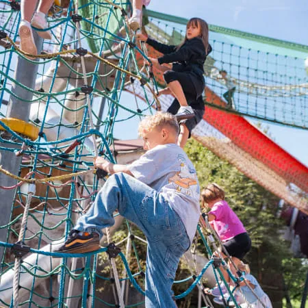 Kinder spielen auf einem Klettergerüst im Erlebnispark.