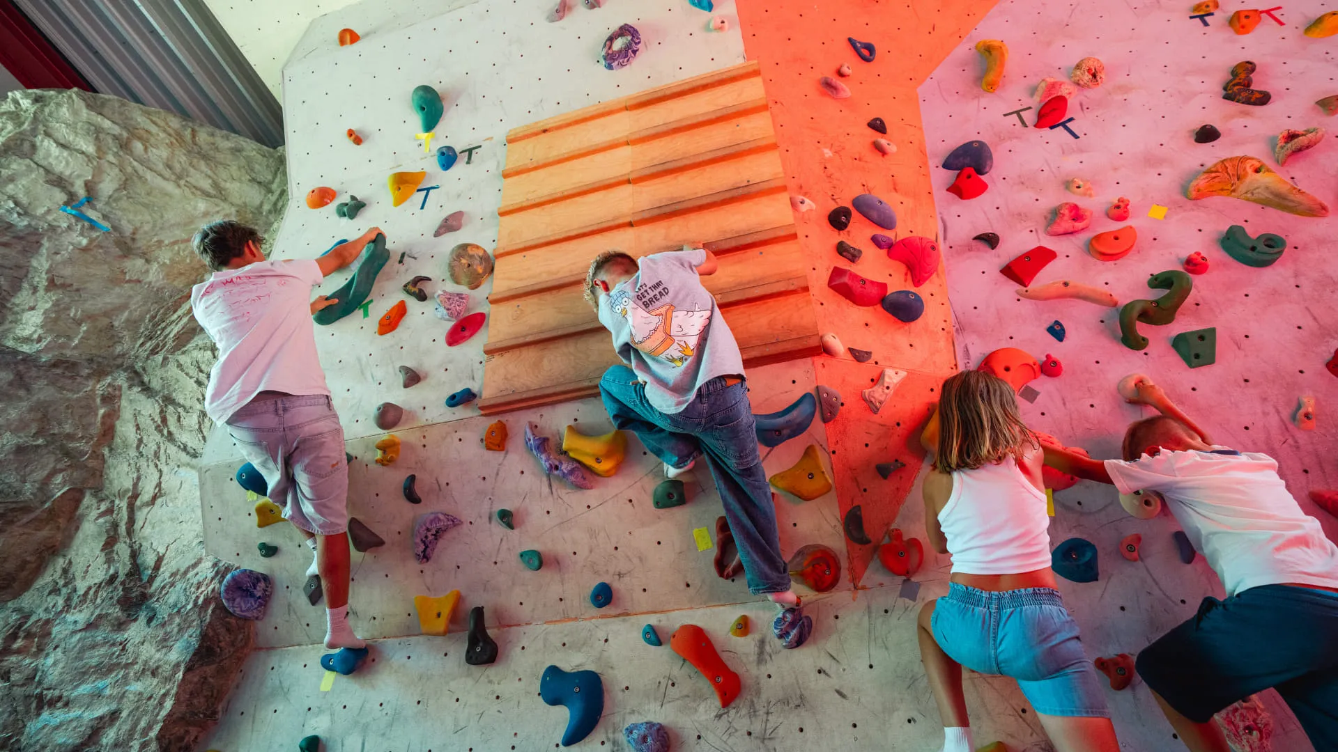 Kinder klettern an einer bunten Kletterwand im Erlebnispark